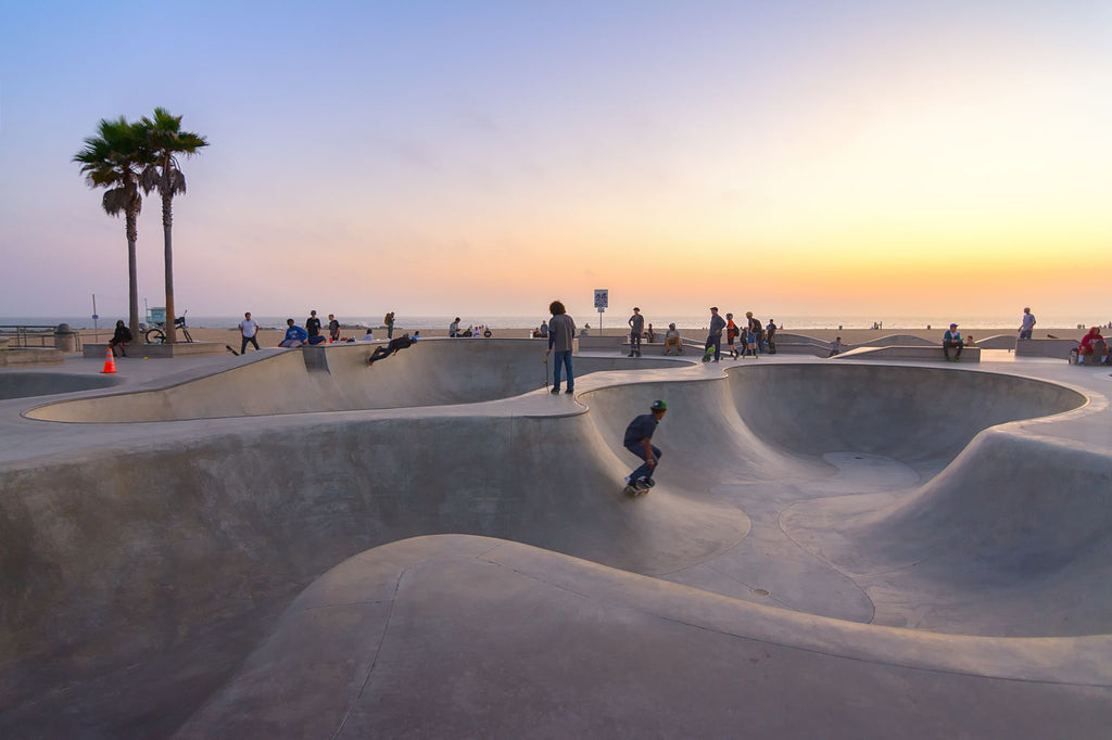 skateboarders at a skate park in venice beach at sunset