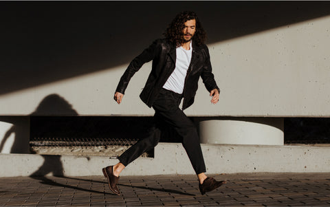 smartly dressed man jumping sideways on the sidewalk