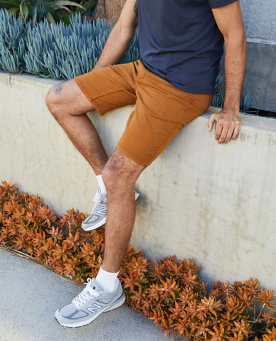 man sitting on a concrete barrier wearing amber shorts and navy polo