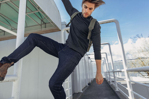 man wearing DUER jeans jumping onto a railing