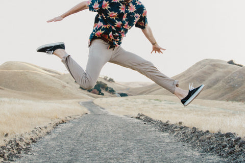 man wearing DUER pants jumping across a path