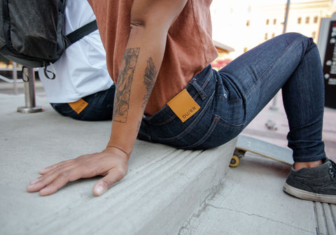 skateboarder wearing DUER jeans sitting on a sidewalks