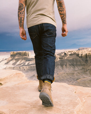 Hiker wearing DUER jeans walking along a rock