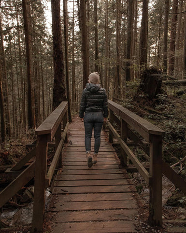 woman walking over a wood path in the woods