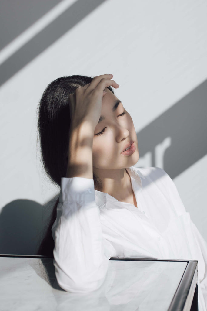 woman leaning on a white table holding her forehead