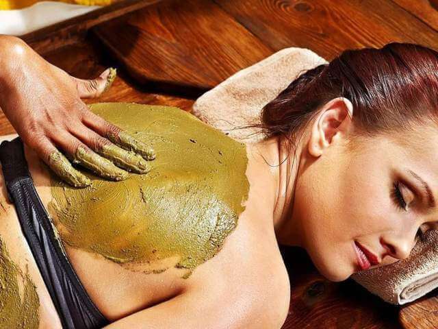 woman being massaged on the back while lying down using Ayurvedic powder
