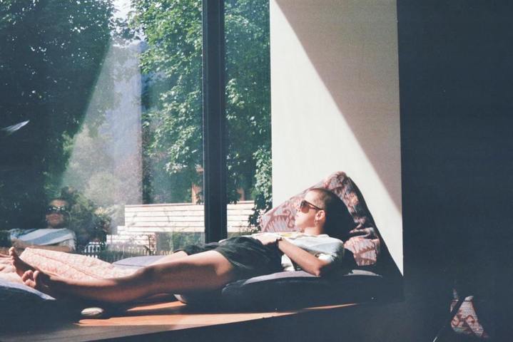 man reclining on a mattress beside a large window relaxing