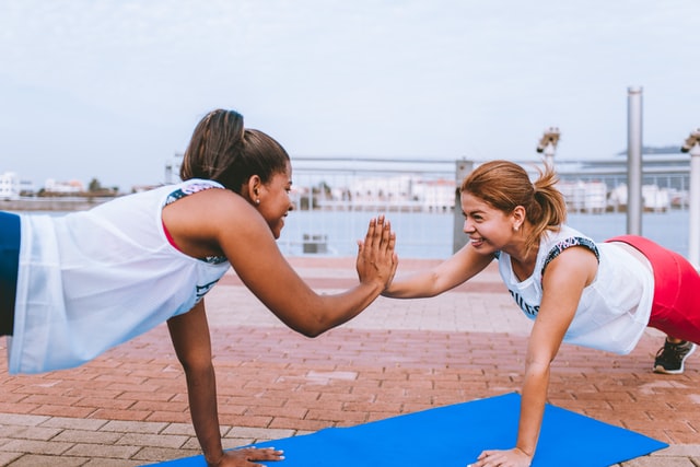 two women doing a couple yoga pose outdoors
