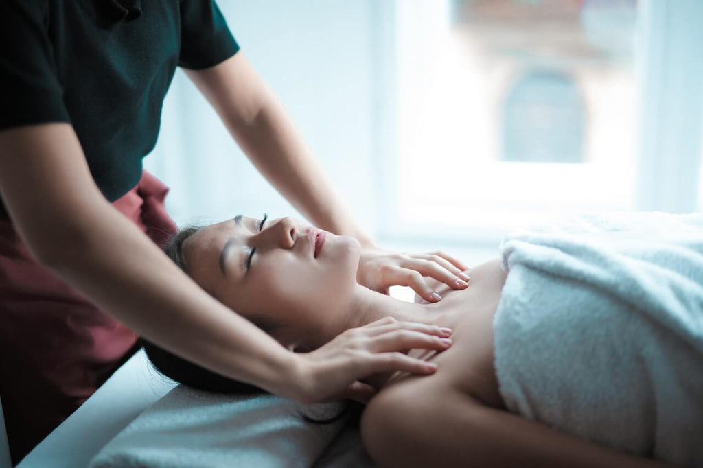 woman lying down while being massaged on the shoulders