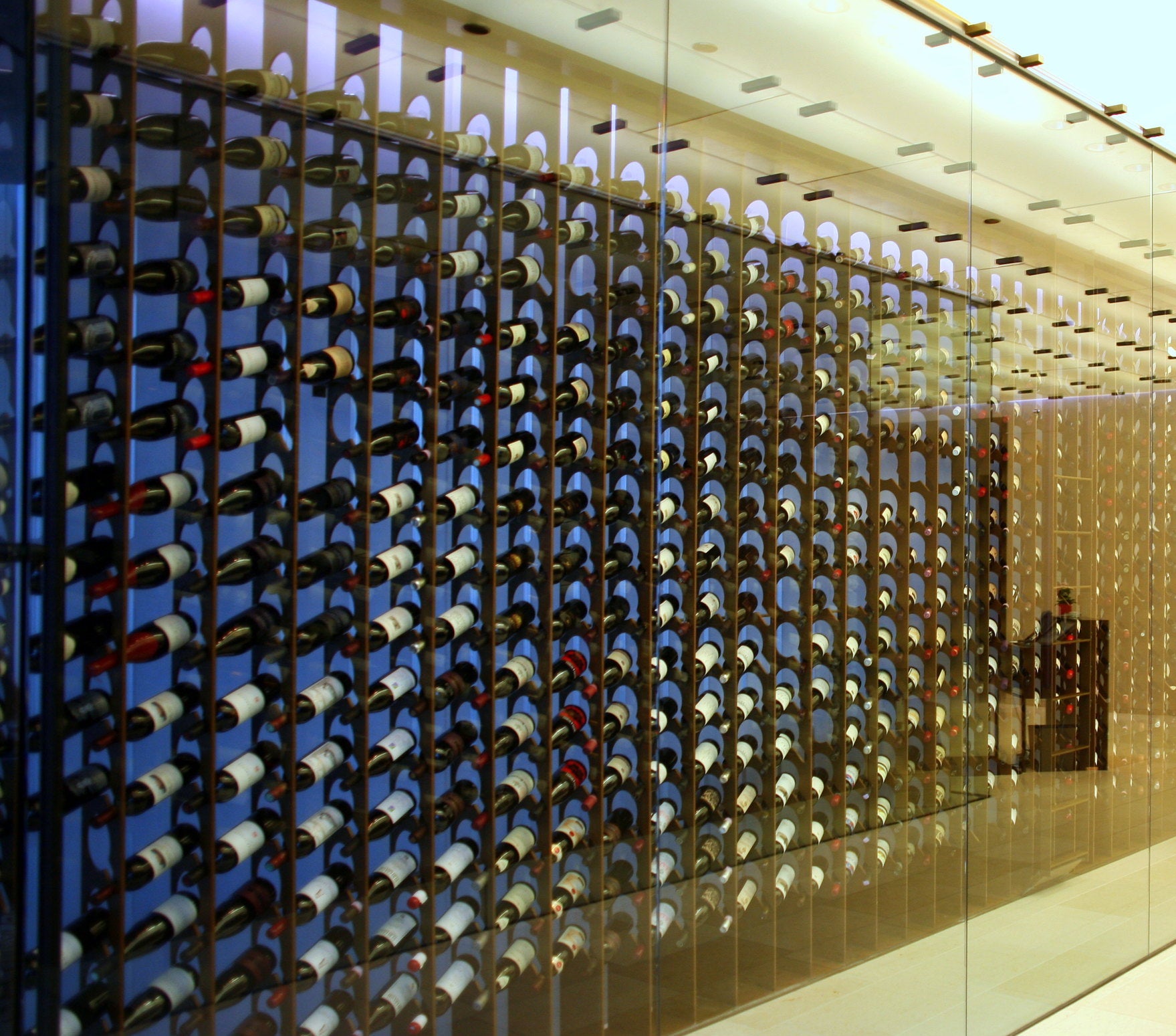 Wine bottles in a wall-mounted wine rack enclosed in glass