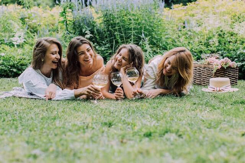 four female friends laughing and drinking wine