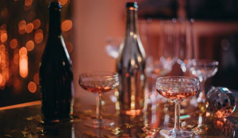 Two wine bottles and two vintage champagne wine glasses with wine on a table