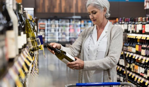 Woman at the store reading the label on a wine bottle