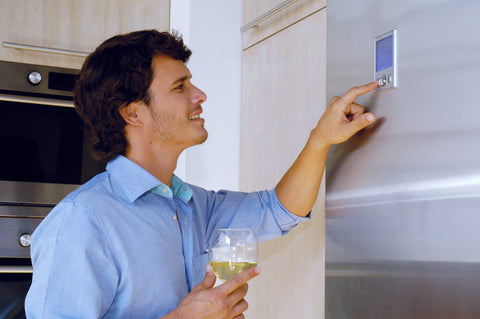 guy holding a wine glass pressing buttons on the fridge