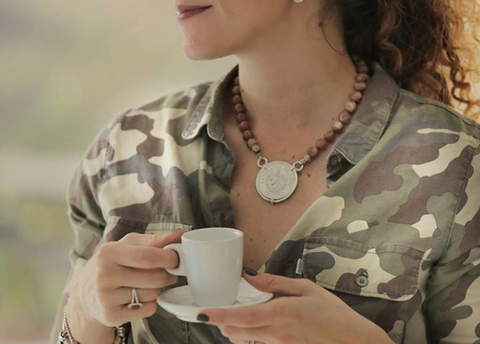 Image of woman drinking coffee and wearing a Cuban necklace and bracelet