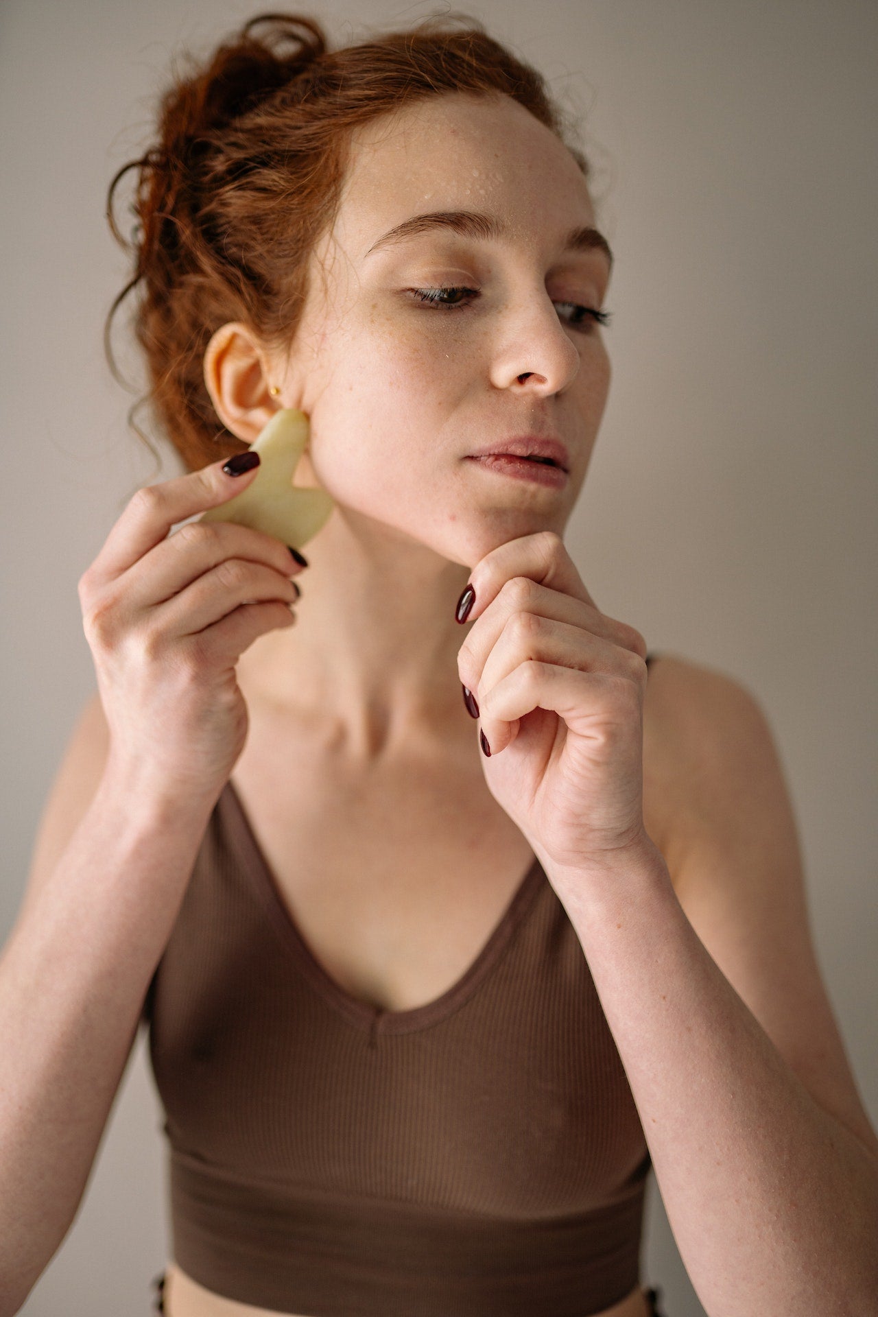  A woman using a gua sha skincare tool for lymph node massage