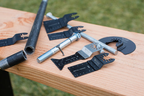 Power tools and Ryker Hardware saw blades on a piece of wood outside.