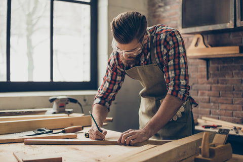 Man in plaid measuring and marking wood to be cut