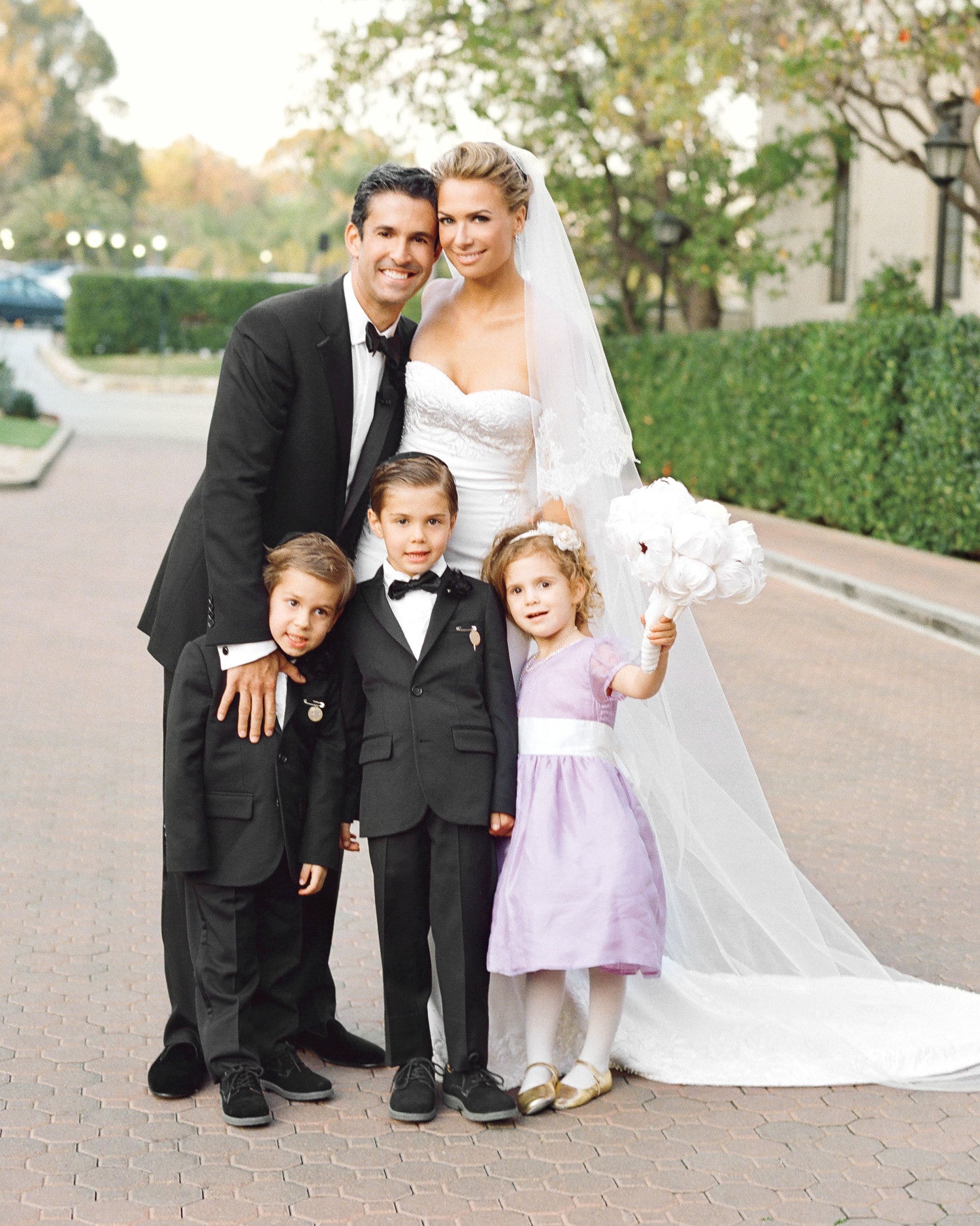 Bride, Groom, and children smile outside of wedding venue.