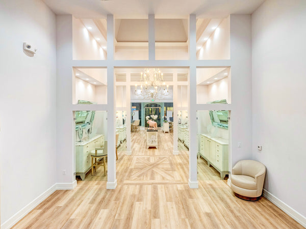 Photo taken from back of store looking towards the entrance. Two large service areas with horizontal mirrors. 
A waiting area is available near service areas. Large chandelier provides luxurious decor and bright light.