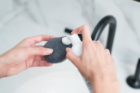 Hands over sink applying Face Foam to Bamboo Charcoal Sponge