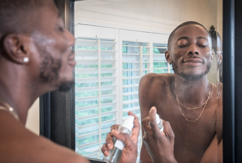 Reflection of man in mirror spritzing Graydon Skincare Face Food Mineral Mist onto face.