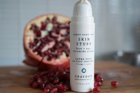 Bottle of Graydon Skincare Skin Stuff Face + Eye Cream in front of half a pomegranate.