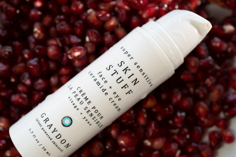 bottle of Graydon Skincare Skin Stuff Face + Eye Cream on a bed of pomegranate seeds