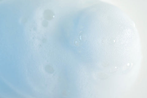 A pump of white foaming fragrance-free cleanser against an off-white background