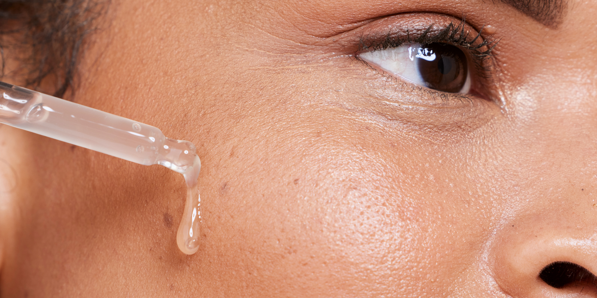 woman applies serum to her face