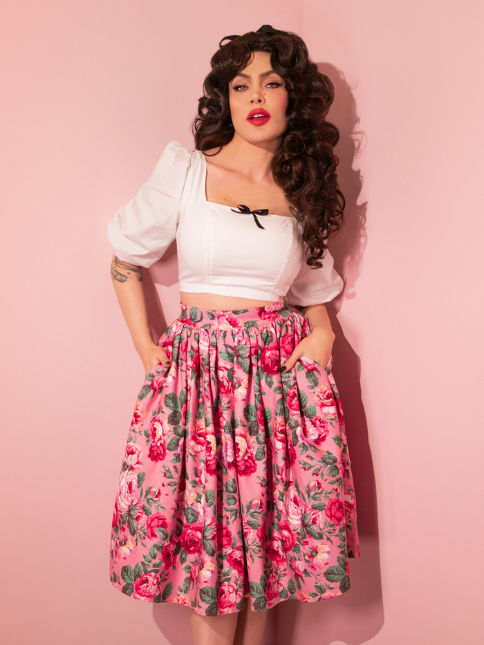 Micheline Pitt tucking her hands into the pockets of her Vixen Swing Skirt in Pink Rose Print.
