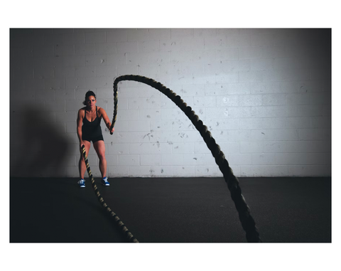 woman using battle ropes in garage 