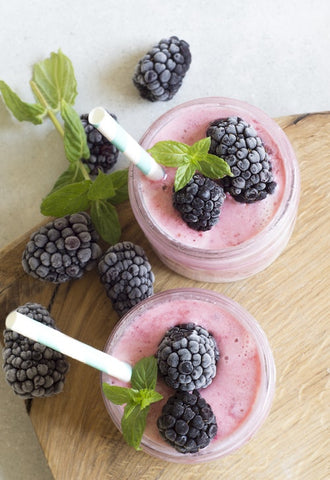 Two blackberry smoothie jars with white straws
