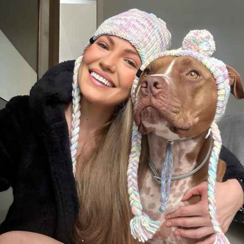 Loving pitbull owner hugging their dog with matching beanies