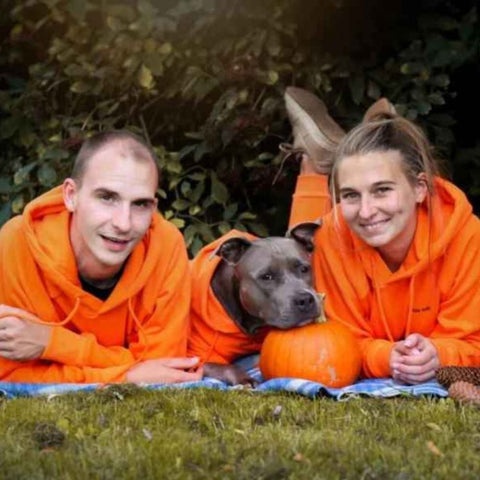 Pitbull with owners in matching orange Sparkpaw hoodies