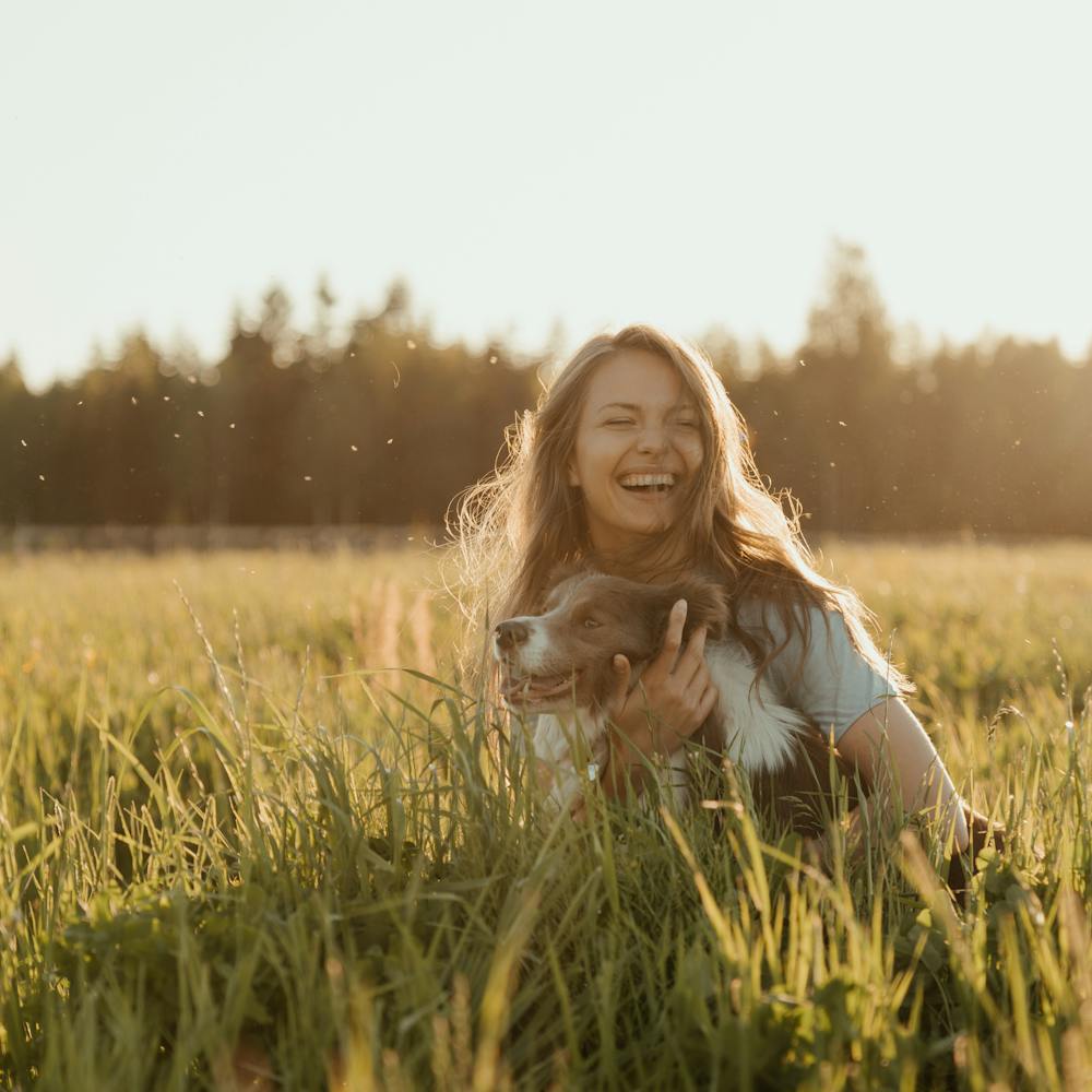 Woman playing with dog on grass under hot weather