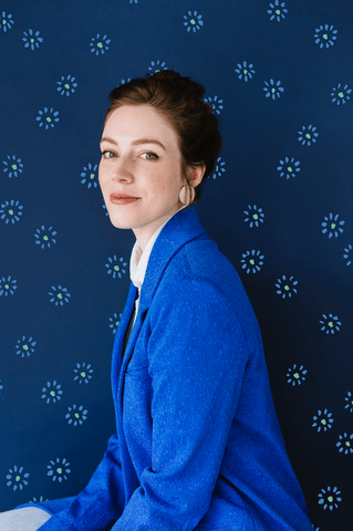 Artist Emily Taylor wearing a blue blazer in front of blue background