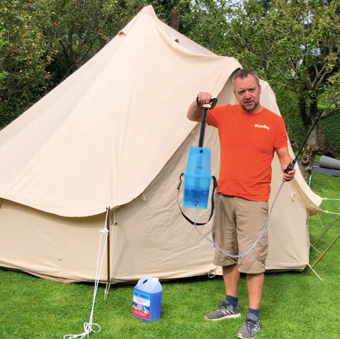 Man holding garden pump pressure sprayer in front of canvas bell tent
