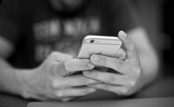Person holding iPhone, black and white photo - Cheating has the potential of ruining a great trivia night, but if handled properly, it’s easy to stop it before it starts.