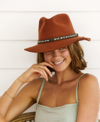 woman smiling while wearing a burnt orange wool sun protection hat and a green top