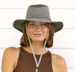 woman wearing a grey boating hat and a brown top smiles at the camera