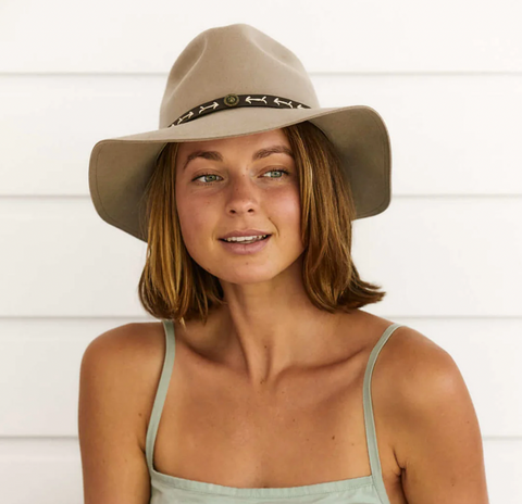 woman wearing a beige boho hat stares into the distance