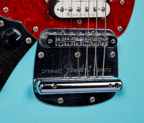 a close up of the blue body and red scratchplate around the bridge of Kurt Cobain's Skystang 1 Fender Mustang guitar