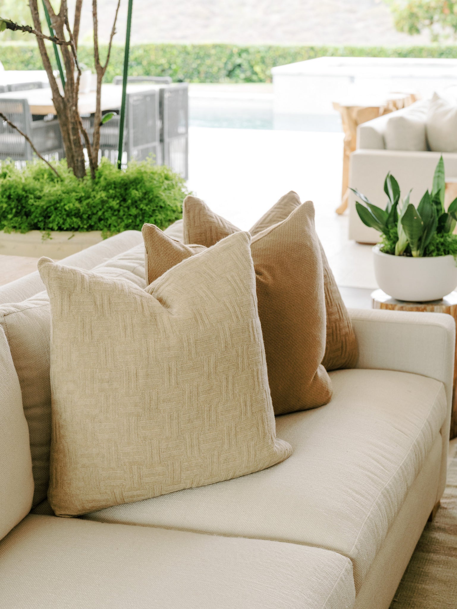 A cozy outdoor seating area with a mix of patio furniture and indoor chairs, adorned with cushions