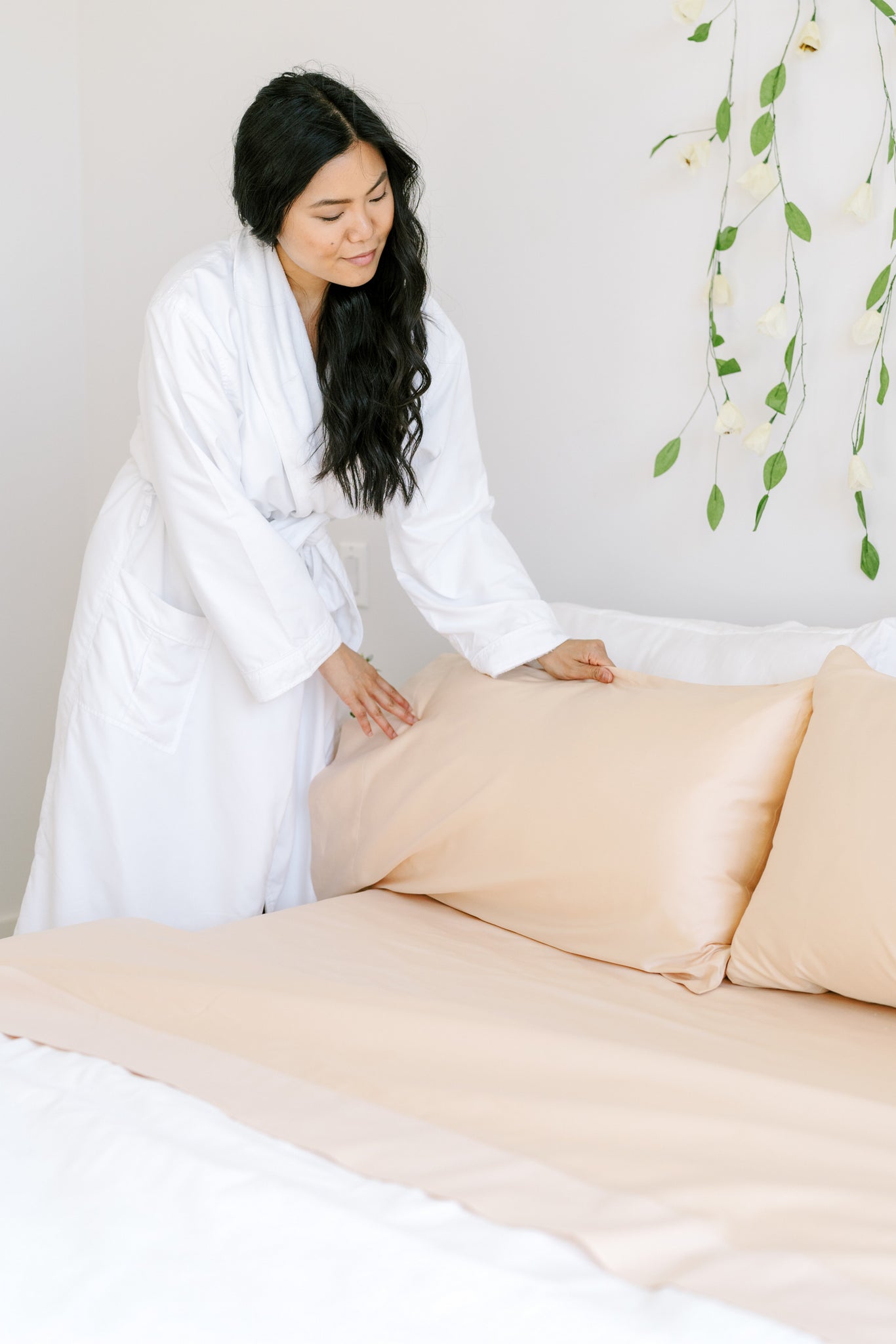 a woman making the bed in her guest bedroom