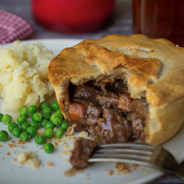 Cut open steak pie with mash and peas