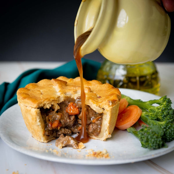 Spring lamb and mint pie on a plate with gravy being poured