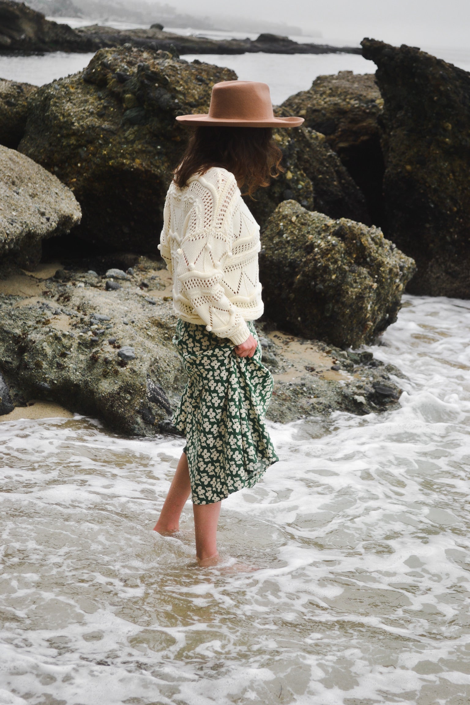 Laura Prietto wearing a sustainable green daisy skirt and hand-knit sweater at the beach in southern California | Thread Spun Blog