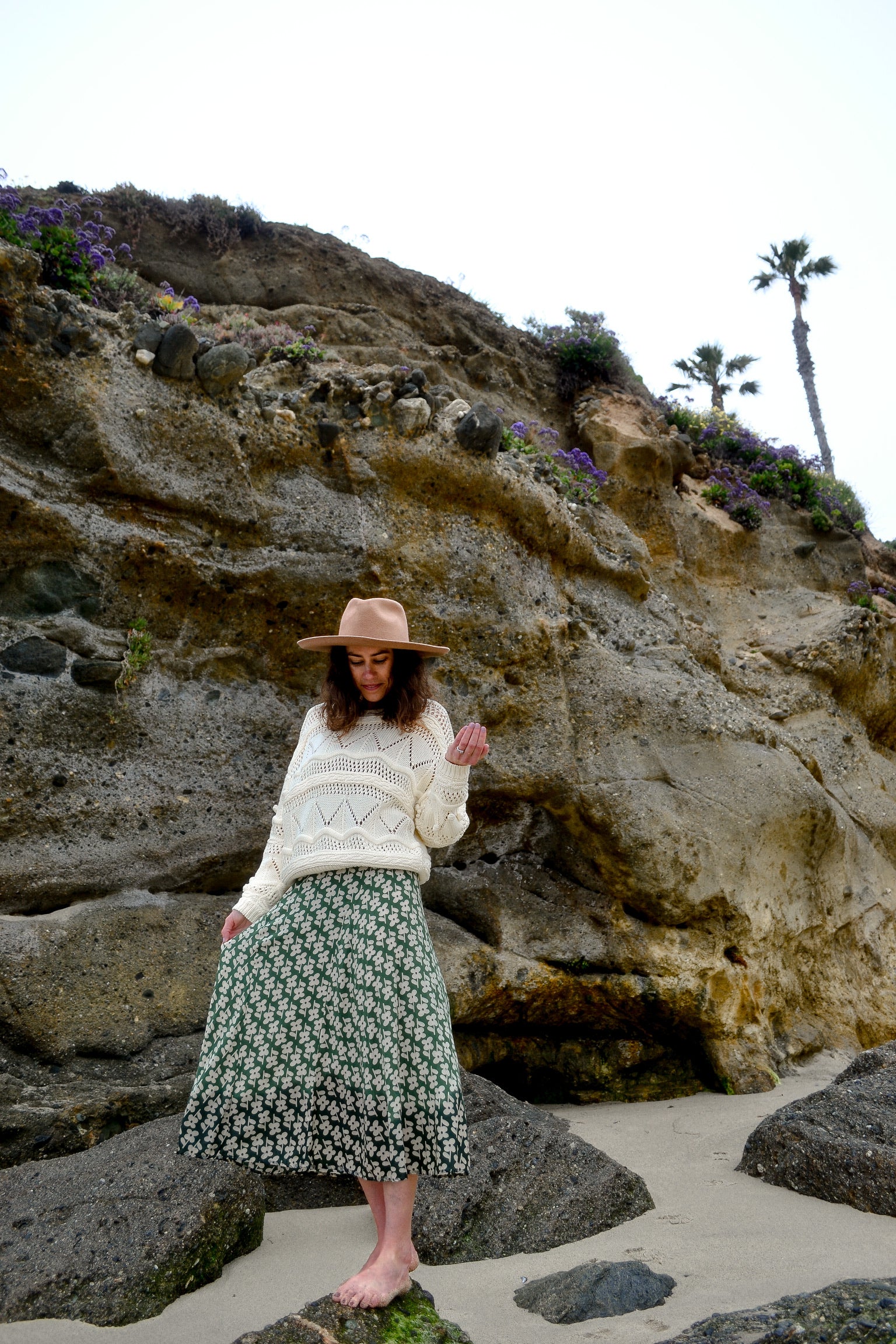 Laura Prietto wearing a sustainably-made sweater by Louise Misha and a sustainable, printed flower skirt sold by Thread Spun