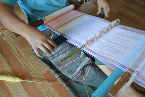 Thread Spun employee Pleh weaving textiles on her loom.
